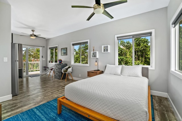 bedroom with access to exterior, wood finished floors, multiple windows, and freestanding refrigerator