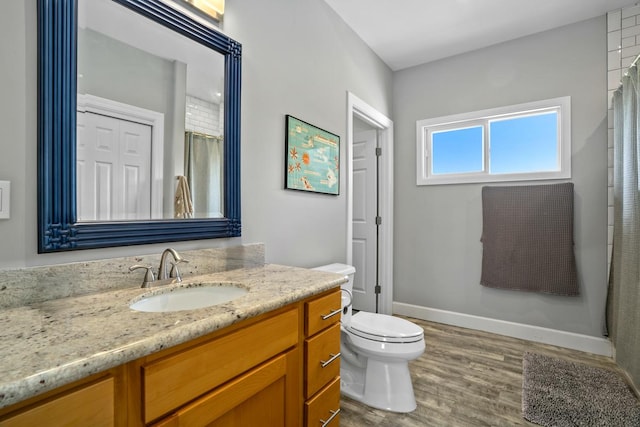 bathroom featuring toilet, vanity, baseboards, and wood finished floors