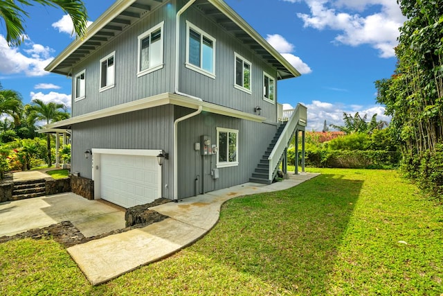 back of property featuring driveway, an attached garage, stairway, and a yard