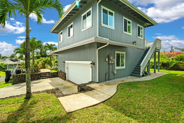 view of side of property featuring a yard, driveway, a garage, and stairway