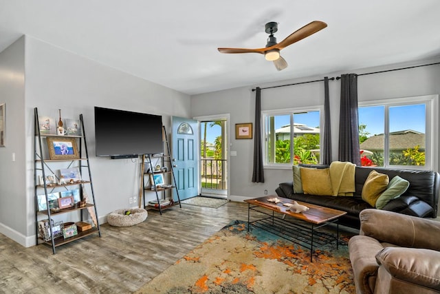 living room featuring baseboards, ceiling fan, and wood finished floors