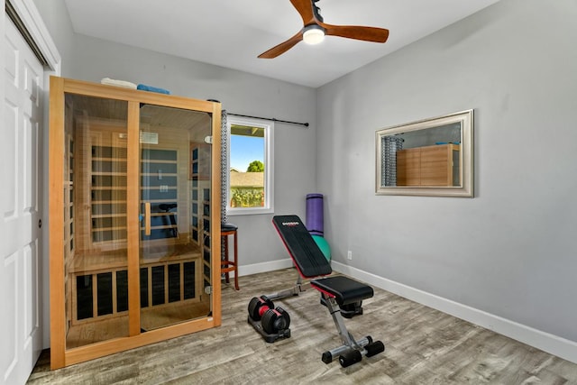 workout area with baseboards, wood finished floors, and a ceiling fan