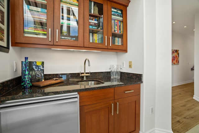 bar featuring wet bar, a sink, wood finished floors, stainless steel dishwasher, and baseboards