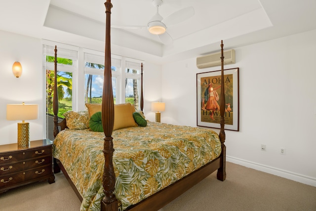 bedroom featuring a wall mounted AC, baseboards, a ceiling fan, a tray ceiling, and light colored carpet