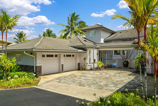 mediterranean / spanish-style house with a tile roof, driveway, stucco siding, and an attached garage