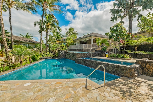 outdoor pool with a jacuzzi and fence