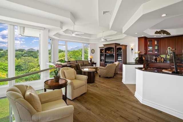 living room featuring a tray ceiling, wood finished floors, visible vents, ceiling fan, and recessed lighting