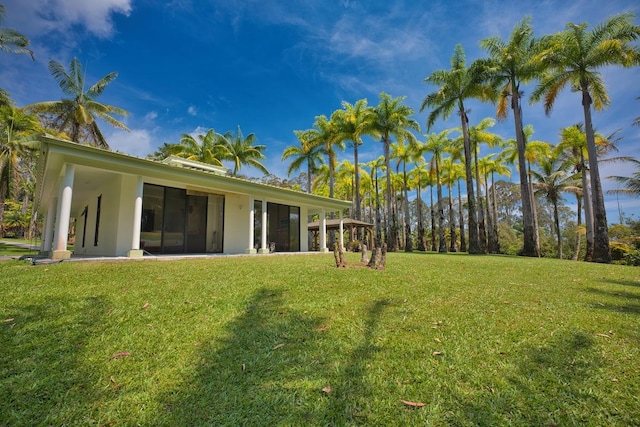 rear view of property with stucco siding and a yard