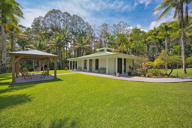 rear view of property with a gazebo, a yard, and a patio area