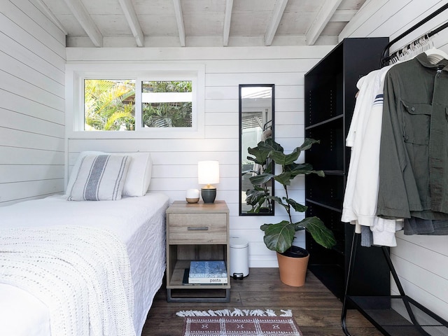 bedroom featuring beamed ceiling, wood finished floors, and wood walls