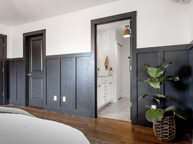 bedroom with a wainscoted wall and wood finished floors