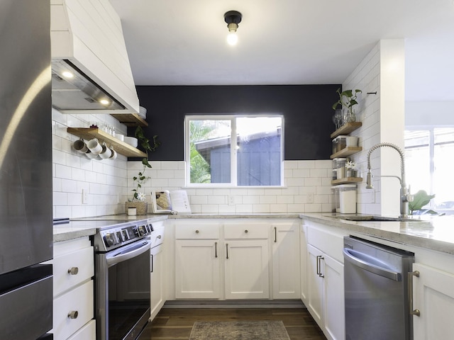 kitchen with wall chimney exhaust hood, a sink, open shelves, and appliances with stainless steel finishes