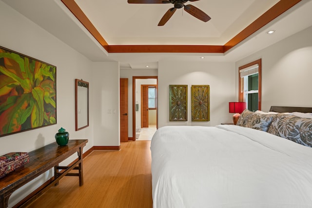 bedroom featuring recessed lighting, light wood-style floors, baseboards, a ceiling fan, and a raised ceiling