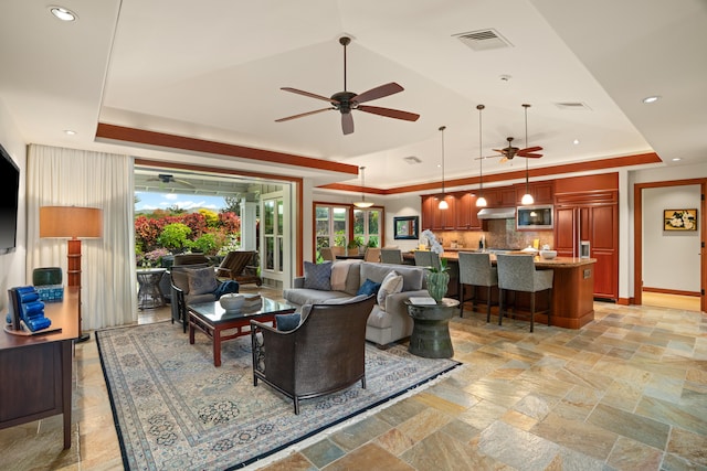 living room with ceiling fan, a tray ceiling, recessed lighting, baseboards, and vaulted ceiling