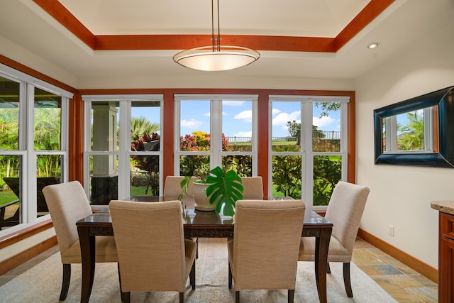 dining space with baseboards, stone tile flooring, a raised ceiling, and recessed lighting