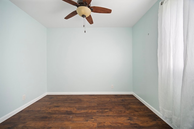 empty room featuring a ceiling fan, dark wood finished floors, and baseboards