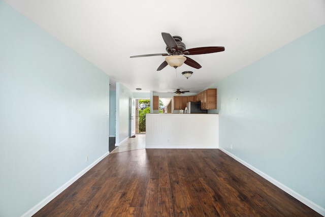 unfurnished living room with a ceiling fan, wood finished floors, and baseboards