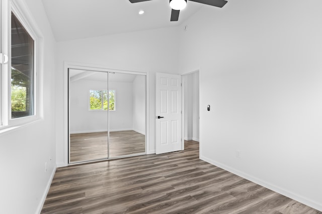 unfurnished bedroom with lofted ceiling, a closet, wood finished floors, baseboards, and ceiling fan