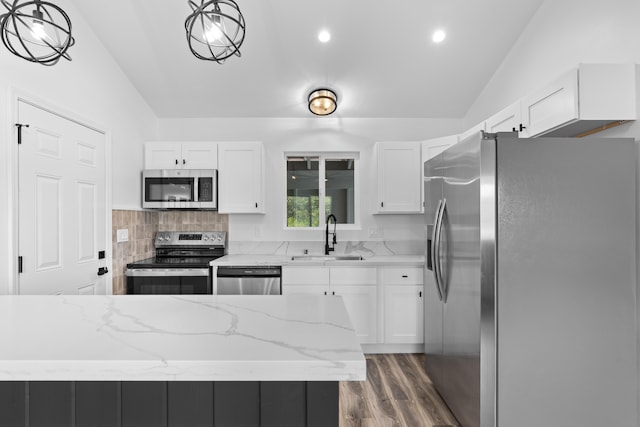 kitchen featuring stainless steel appliances, a sink, vaulted ceiling, dark wood-type flooring, and white cabinets