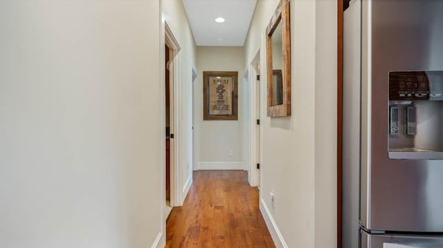 corridor with baseboards and wood finished floors