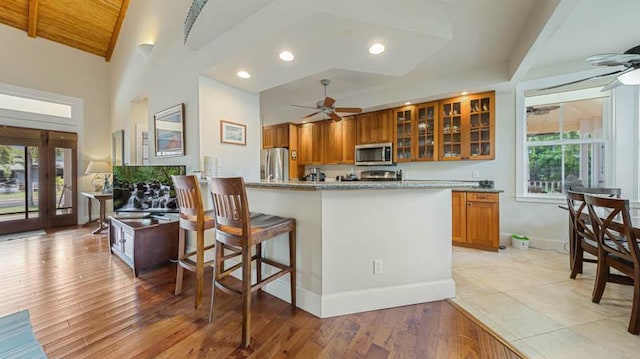 kitchen with stainless steel appliances, brown cabinetry, and ceiling fan