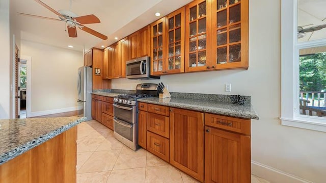kitchen featuring glass insert cabinets, brown cabinetry, a ceiling fan, recessed lighting, and appliances with stainless steel finishes