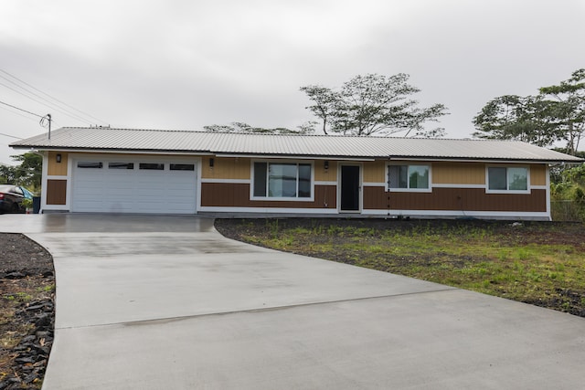 single story home featuring an attached garage, driveway, and metal roof