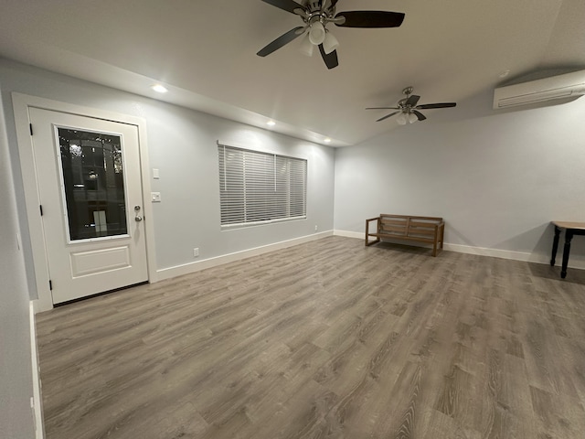 unfurnished living room with a wall mounted AC, ceiling fan, recessed lighting, wood finished floors, and baseboards