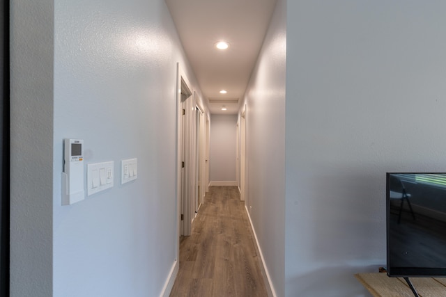 corridor with recessed lighting, light wood-style floors, and baseboards