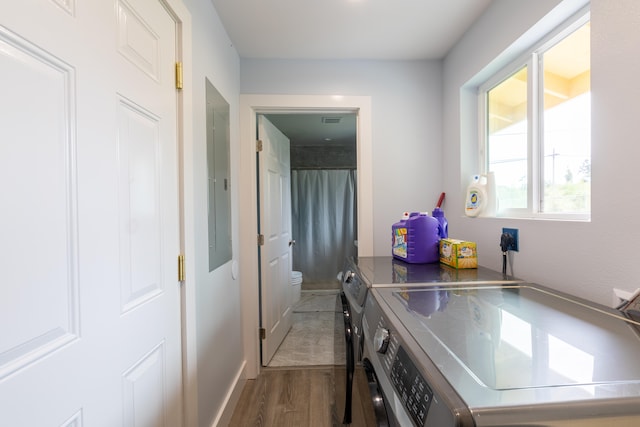 clothes washing area featuring separate washer and dryer and wood finished floors