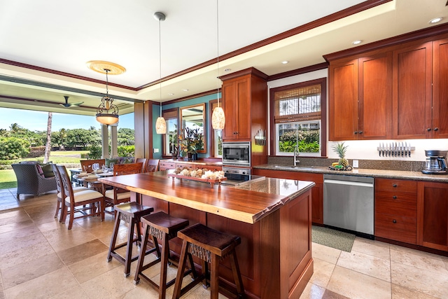kitchen with butcher block countertops, a breakfast bar, stainless steel appliances, ornamental molding, and pendant lighting