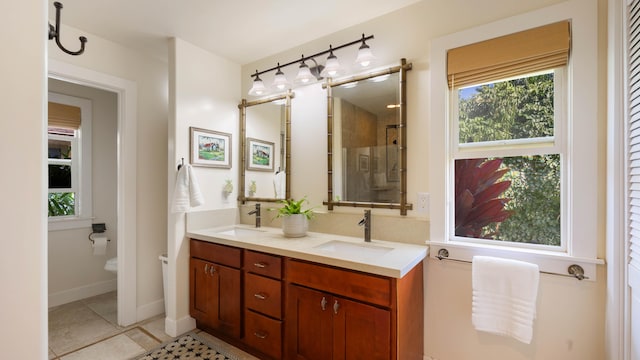 full bathroom with a sink, double vanity, and a wealth of natural light