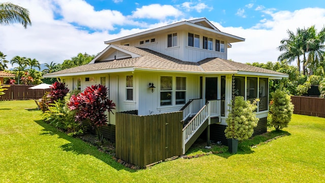 back of property with a sunroom, a lawn, fence, and roof with shingles