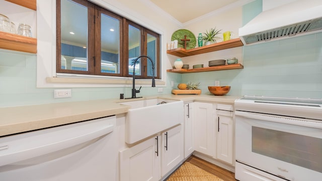 interior space featuring decorative backsplash, crown molding, a sink, white appliances, and wall chimney exhaust hood