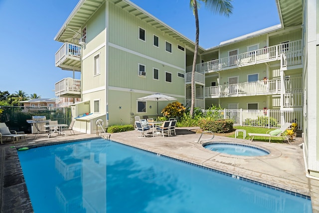 community pool featuring fence, a community hot tub, and a patio area