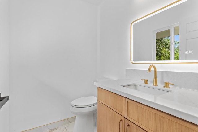 bathroom featuring marble look tiles, toilet, and vanity