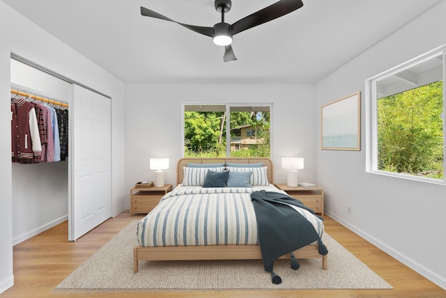 bedroom featuring light wood-type flooring, baseboards, a ceiling fan, and a closet