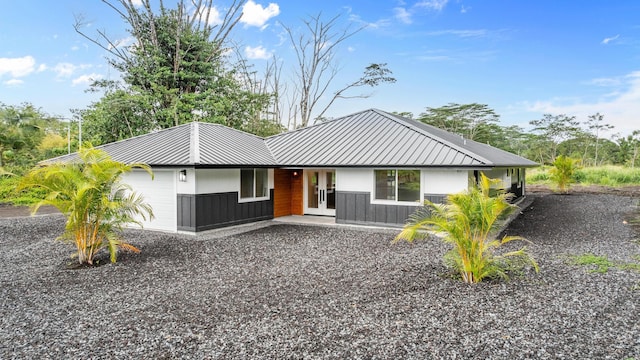 view of front of property with french doors, metal roof, driveway, and a garage