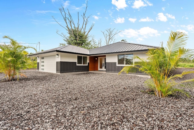 view of front of property featuring a garage, gravel driveway, and metal roof