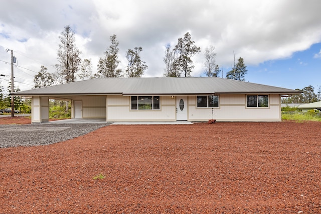 ranch-style house featuring a carport, metal roof, and gravel driveway