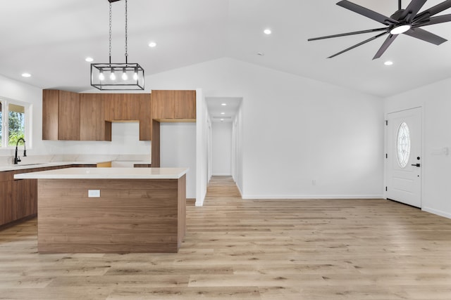 kitchen with brown cabinetry, a sink, modern cabinets, and vaulted ceiling