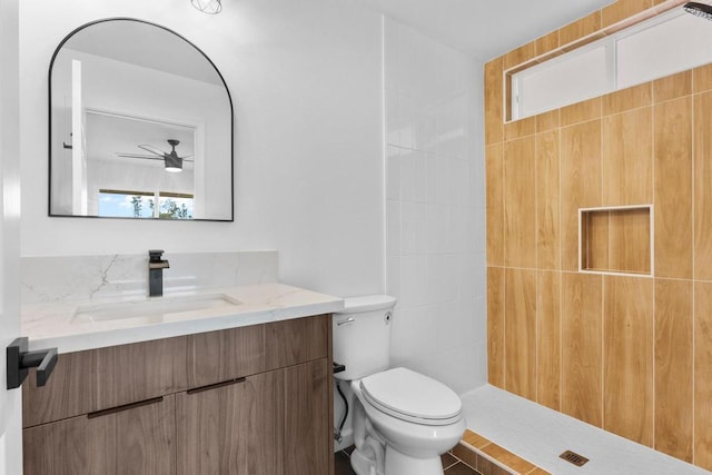 full bathroom with toilet, a tile shower, and vanity