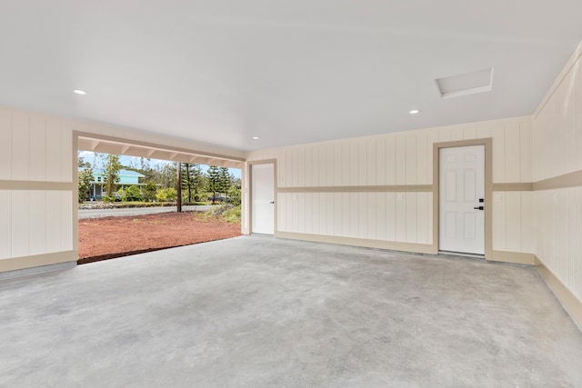 empty room featuring attic access, concrete flooring, and a decorative wall