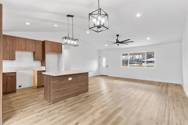 kitchen with brown cabinetry, a kitchen island, vaulted ceiling, ceiling fan with notable chandelier, and recessed lighting