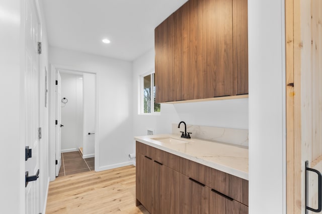 laundry room featuring cabinet space, washer hookup, a sink, light wood finished floors, and baseboards