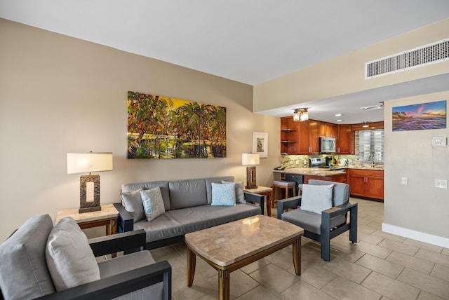 living room featuring light tile patterned flooring, visible vents, and baseboards