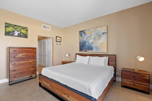 bedroom with light tile patterned flooring, a closet, visible vents, and baseboards