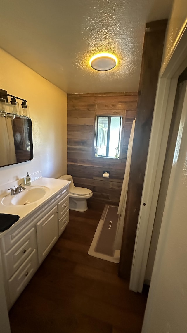 45-1181 Kalehua Rd, Honokaa, HI 96727 - bathroom featuring a textured ceiling, toilet, wooden walls, vanity, and wood finished floors