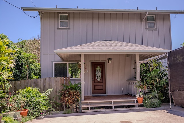 view of front facade featuring fence, roof with shingles, and board and batten siding