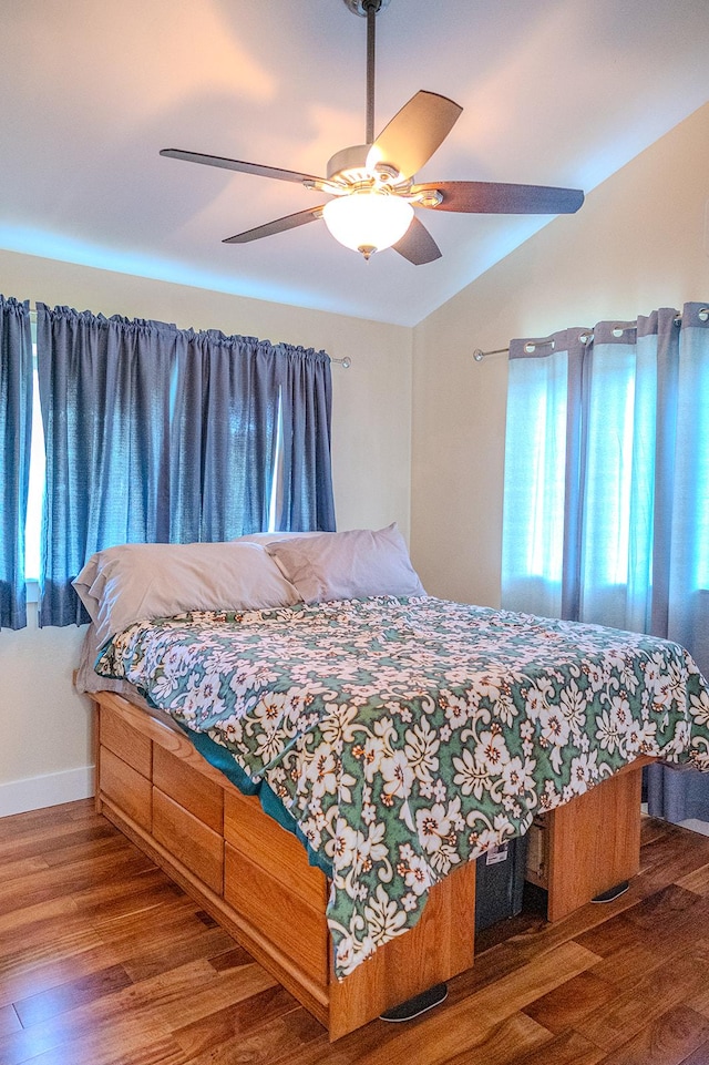 bedroom with lofted ceiling, baseboards, a ceiling fan, and wood finished floors